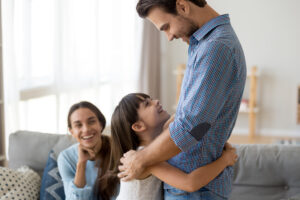 girl embracing father; both are smiling